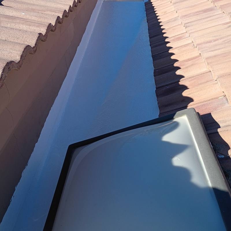 Coated wall to wall: A narrow channel between tile roofs, sealed right up to the skylight.