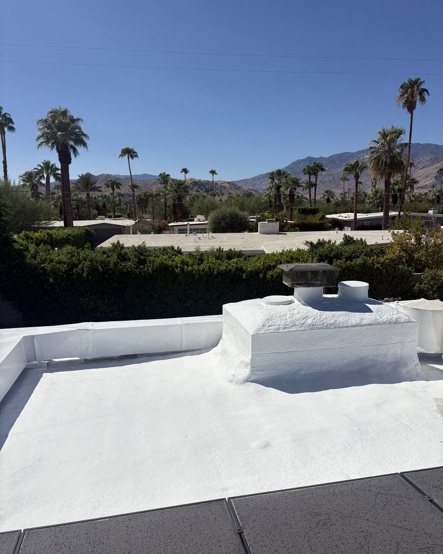 Finished foam roof with coated parapets and chimney below the mountains