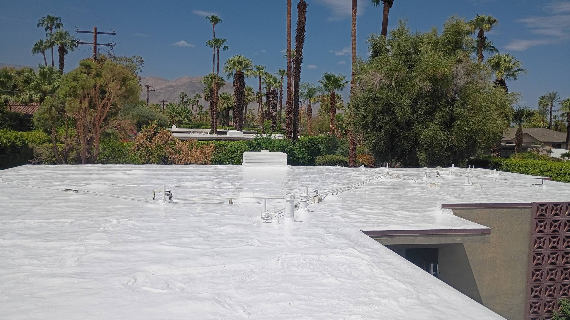 Fresh white foam roof on a mid-century desert home with a breeze-block wall