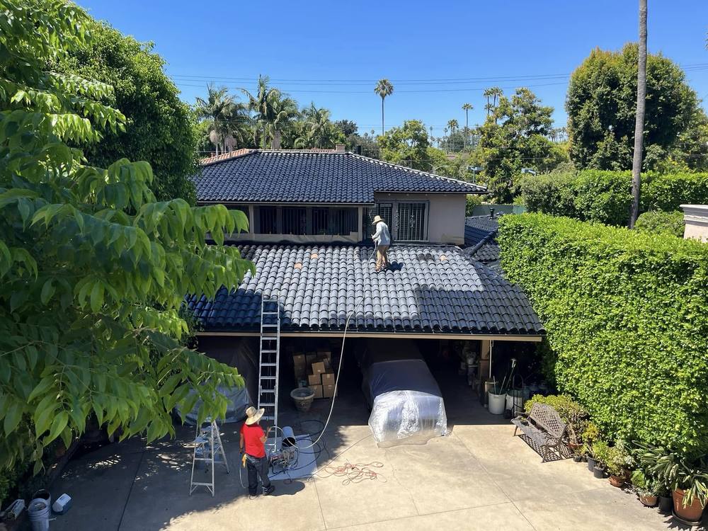 Crew painting a concrete tile roof on a two-story home